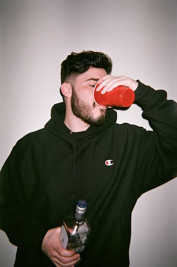 Man in Champion Hoodie Drinking from Red Cup