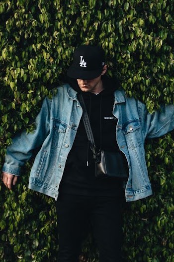 man in denim jacket beside bush