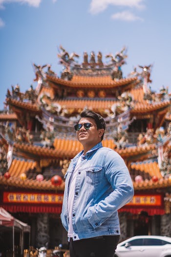 Man in Denim Shirt and wearing sunglasses standing in front of a temple