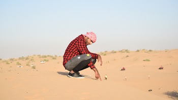 Man in Flannel Shirt Sitting on Sand