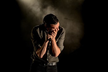 Man in Gray Dress Shirt Holding Mic in Dark Room