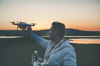 Man in Gray Jacket Holding Black Drone