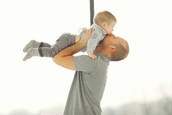 Man in Gray Short Sleeve T-shirt Carrying Baby