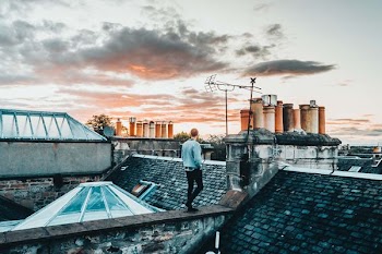 man in gray sweater standing on roof abn