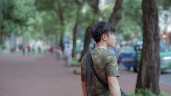 Man in Green and Grey Camouflage Shirt While Standing Behind Tree