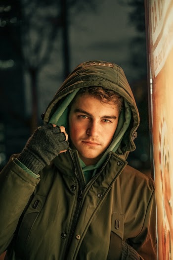 Man in Green Jacket Leaning Beside Wall