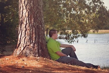 Man in Green Polo Shirt Sitting Beside Tree