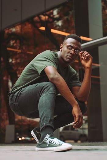 Man in Green Tee Shirt Squatting While Holding Her Eyeglasses