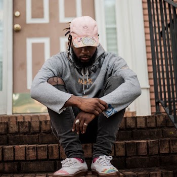 Man in Grey Hoodie, Grey Distressed Denim Jeans, and Pink Hat Sitting on House Front Steps