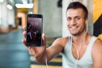 Man in gym holding smartphone mockup Free Psd
