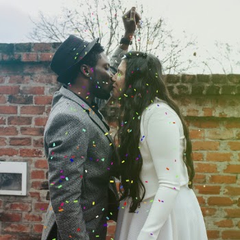 Man in Hat Kissing Woman in White Dress