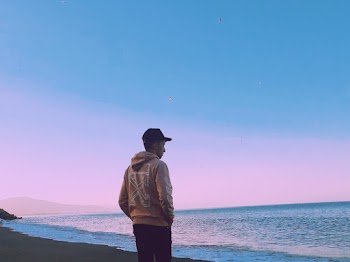 Man In Hoodie Standing On Seashore