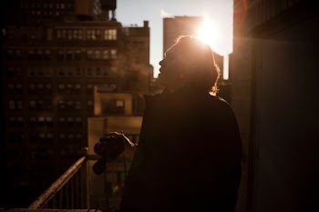 man in jacket holding camera on balcony during daytime
