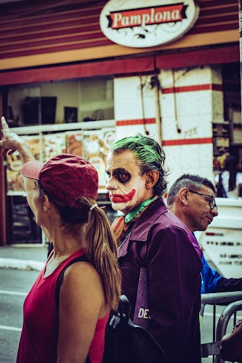 Man in Joker Costume Standing Beside Woman in Red Cap