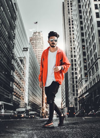 Man In Orange Jacket Standing On Street In Between High Rise Buildings