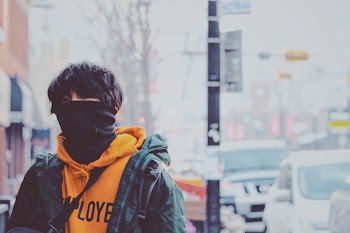 Man in Orange Pullover Hoodie and Green Jacket Covered With Black Mask