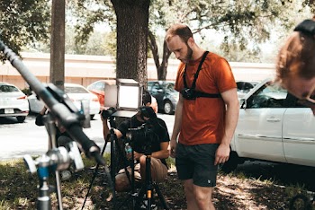Man in Orange T-shirt and Black Shorts Checking On The Cameras