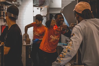 Man in Orange Top Holding Smartphone