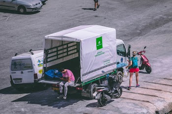 Man in Pink Shirt Sitting at the Back of White Truck