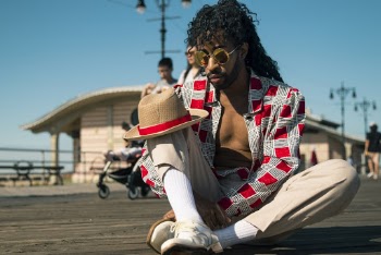 Man in Red and Gray Dress Shirt Sitting on Ground