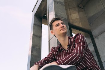 Man in Red and White Striped Dress Shirt Posing Near Wall