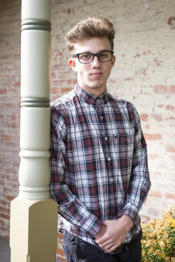 Man in Red Black and White Plaid-printed Dress Shirt Wearing Wayfarer Eyeglasses Leaning on White Wooden Post