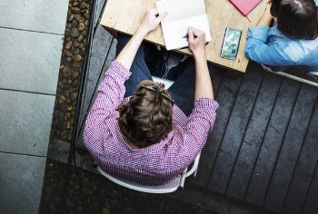 Man in Red Top Writing on Paper