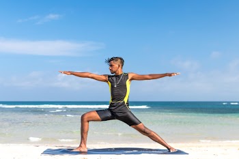 Man in Sleeveless Wet Suit Doing Some Aerobics at the Beach