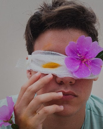 Man in Teal Crew Neck Shirt With Purple Flower on His Head