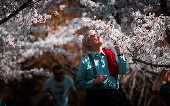 man in teal dress shirt smelling white flower