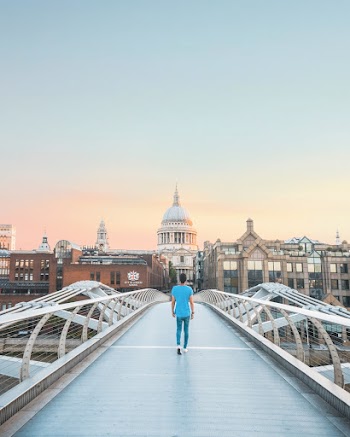 Man in Teal Shirt Walking on Bridge