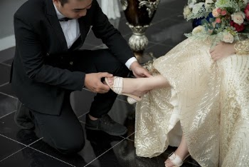 Man in Tuxedo Putting White Sandal on Sitting Woman