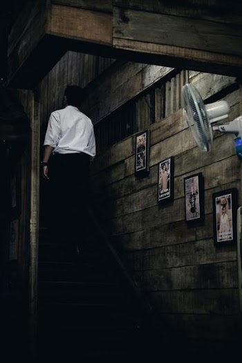 man in white dress shirt and black dress pants walking upstairs inside brown house