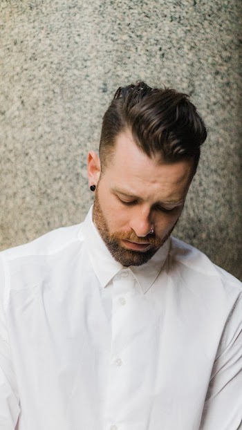 Man in White Dress Shirt Beside Wall Looking Down