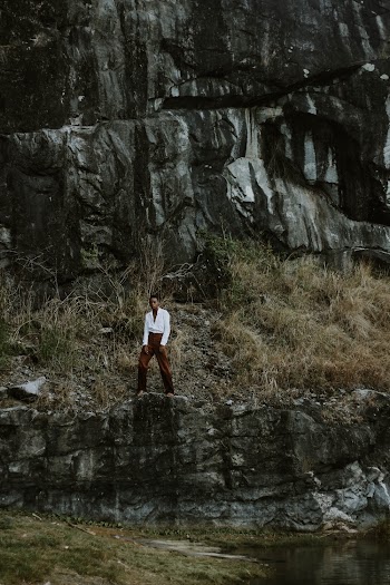 Man in White Long-sleeved Shirt and Maroon Pants Standing Near Cliff