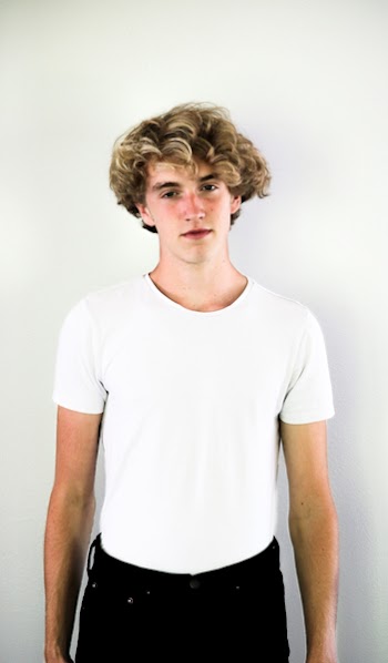 Man in White Shirt and Black Bottoms Standing Against White Wall