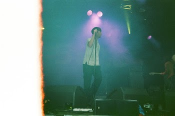 Man in White Shirt and Black Pants Singing on Stage