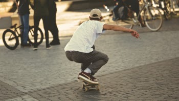 Man in White Shirt and Brown Jeans Riding Skateboard