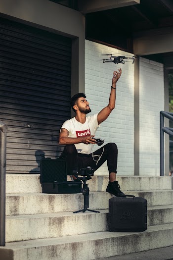 Man in White Shirt Holding Remote of a Drone