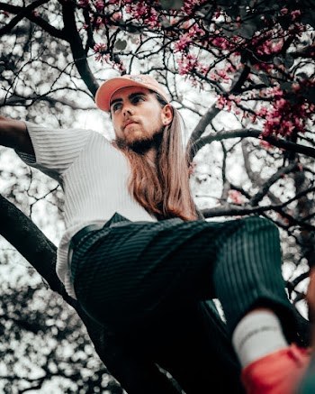 Man In White Shirt Leaning On Tree