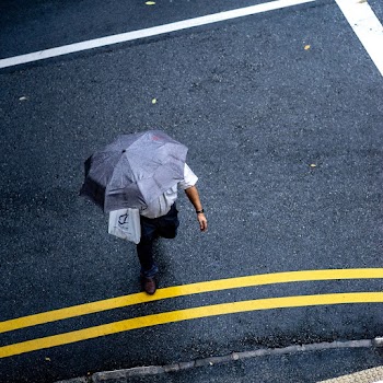 Man in White T-shirt and Blue Jeans Holding Gray Umbrella