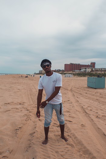 Man in White T-shirt and Blue Jeans Standing on Sand