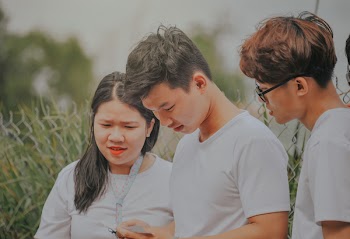 Man in White T-shirt Looking Into His Phone