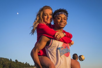 Man In White Tank Top Carrying Woman In Red Jacket