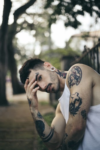 Man in White Tank Top Leaning on Black Fence