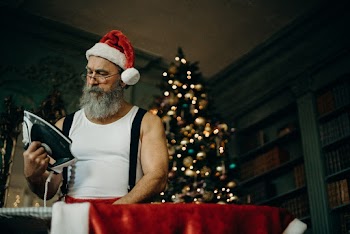 Man in White Tank Wearing Santa Hat Holding Black and Gray Dry Iron