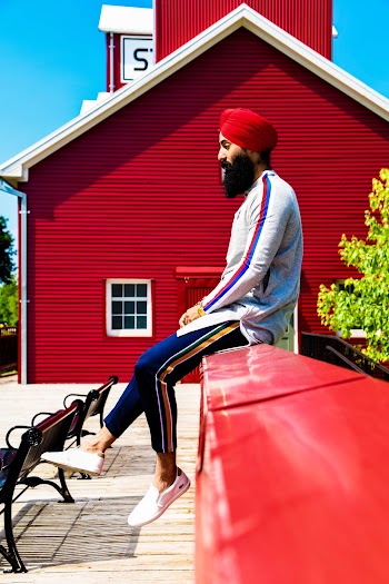 Man in White Top and Red Turban Sitting on Wall