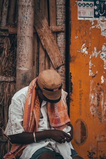 Man in White Top Holding Cloth Beside Brown Wall
