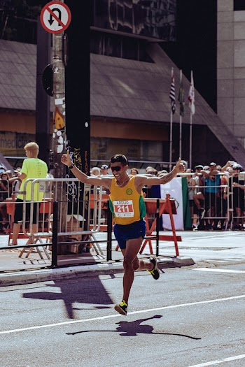 Man in Yellow Tank Top and Black Shorts Running on Street