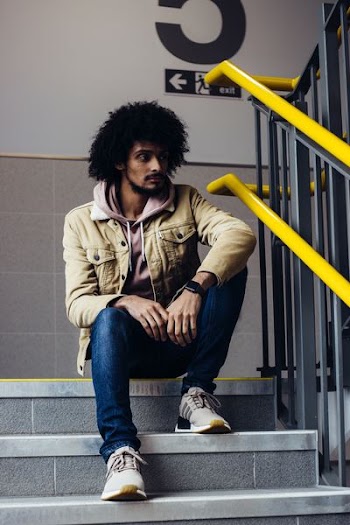 man in zip-up jacket sitting on staircase